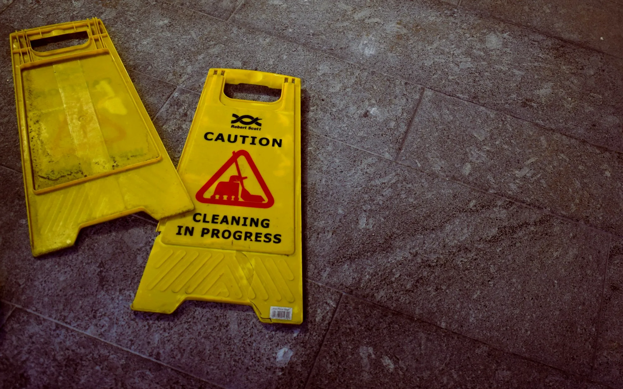 Yellow caution sign that reads cleaning in progress on a tile floor