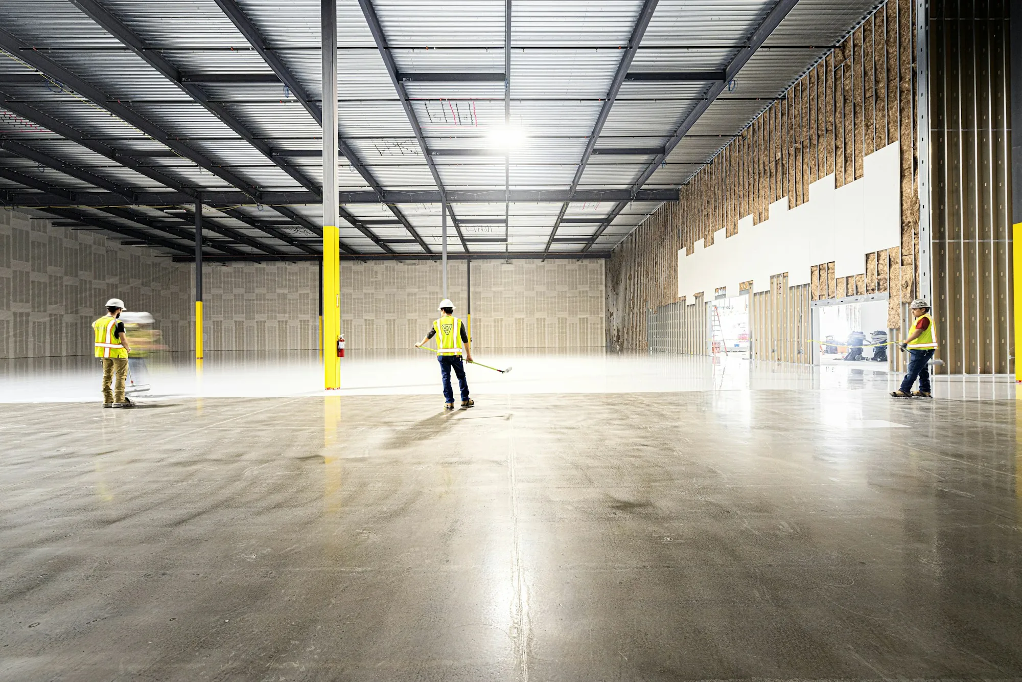 Workers in hi-vis vests in a new, empty warehouse